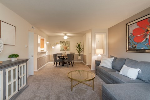 A living room with a grey couch, a coffee table, and a dining table with chairs.