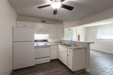 Kitchen in the 420 sq. ft. studio at Village East Apartments in Franklin, Ohio, with white cabinets, electric range, refrigerator, and a breakfast bar overlooking the living space.