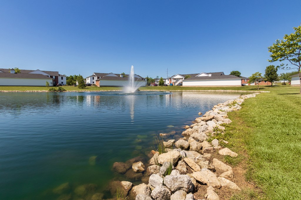 This is a photo of a pond with a fountain and building exteriors at Washington Place Apartments in Miamisburg, Ohio in Washington Township.