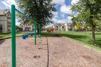 This is a photo of some swings looking towards the playground at The Sanctuary at Fishers in Fishers, IN.