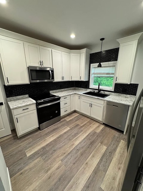 A kitchen with white cabinets and a black countertop.