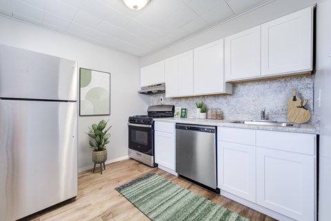 A kitchen with a refrigerator, oven, and sink.