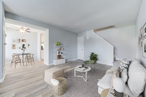 A living room with a white couch, a coffee table, and a dining table with chairs.
