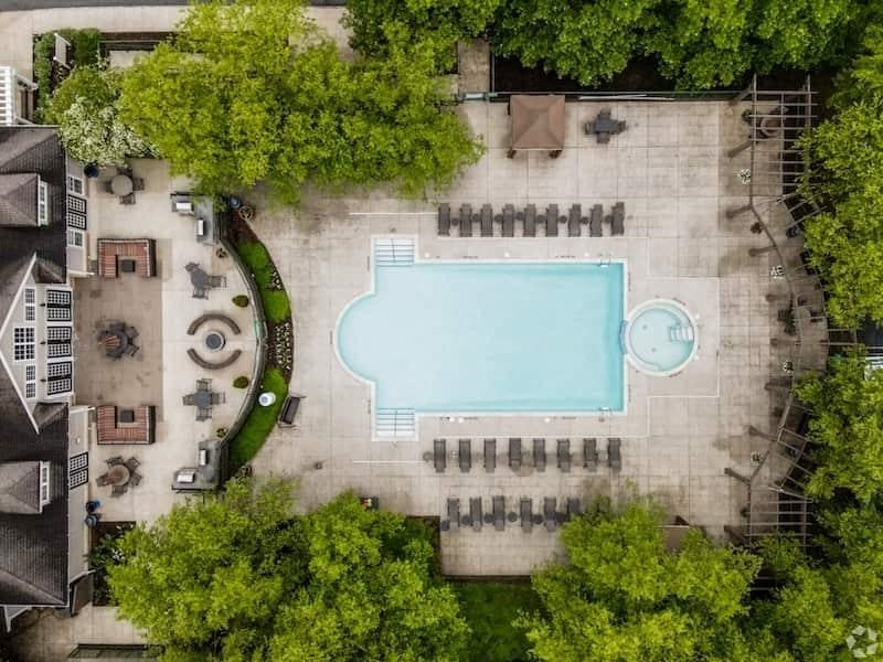 An aerial view of a swimming pool surrounded by trees and a building.at Riverview Landing @ Valley Forge, Pennsylvania, 19403