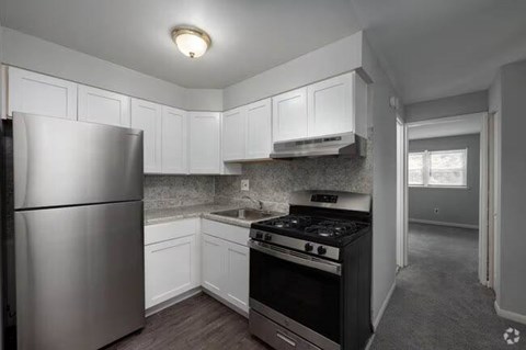 A kitchen with white cabinets and a stainless steel refrigerator.