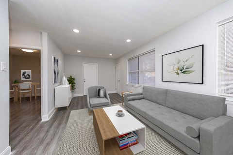 A living room with a grey couch, a coffee table, and a painting on the wall.
