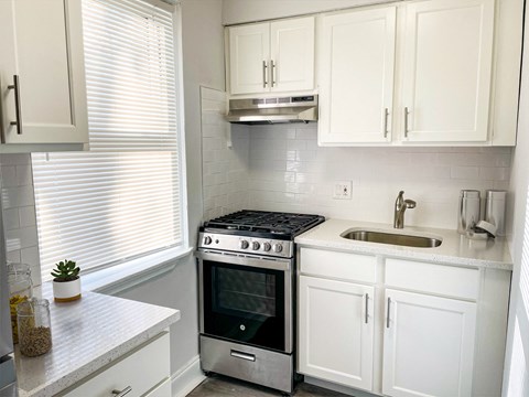 A modern kitchen with white cabinets and a stainless steel oven.
