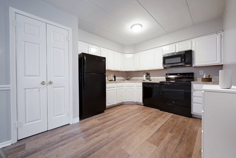 A kitchen with black appliances and white cabinets.