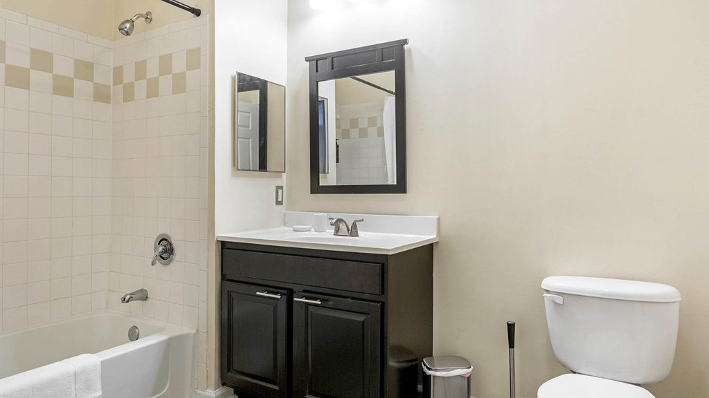 A bathroom with a white toilet, a white sink, a black vanity, and a white bathtub.at Riverview Landing @ Valley Forge, Pennsylvania