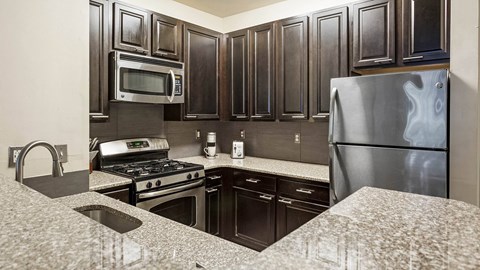 A kitchen with dark wood cabinets and stainless steel appliances.