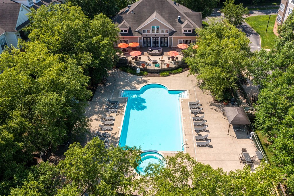 An aerial view of a swimming pool surrounded by trees and a building with a patio.at Riverview Landing @ Valley Forge, Eagleville, 19403