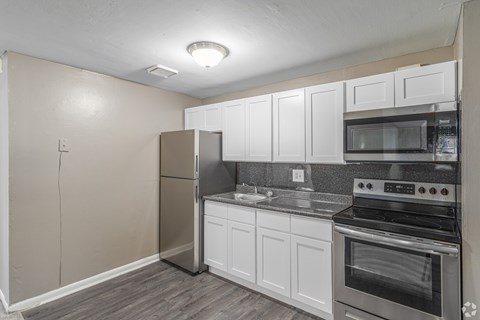 A kitchen with white cabinets and a stainless steel refrigerator.