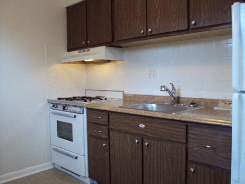 A white gas stove is in a kitchen with brown cabinets.