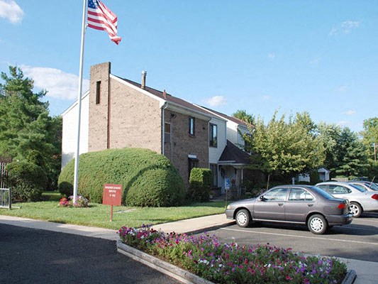 a building with an flag in front of a parking lot a building with an flag in front of a parking lot at Brookshire Trace Townhomes Apartments, Philadelphia, PA