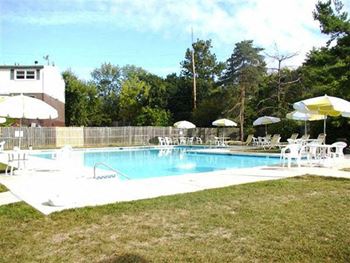 a swimming pool with tables and chairs and umbrellas at Brookshire Trace Townhomes Apartments, Philadelphia