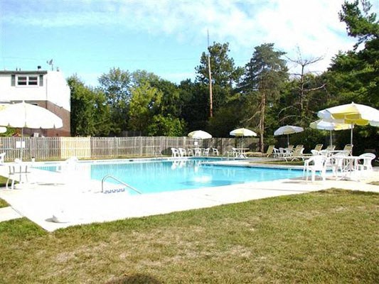 a swimming pool with tables and chairs and umbrellas a swimming pool with tables and chairs and umbrellas at Brookshire Trace Townhomes Apartments, Philadelphia, 19116
