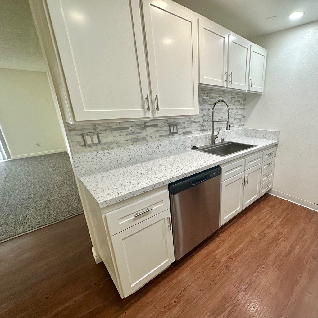 a kitchen with white cabinets and a stainless-steel dishwasher  at Willow Tree Apartments, California, 90505