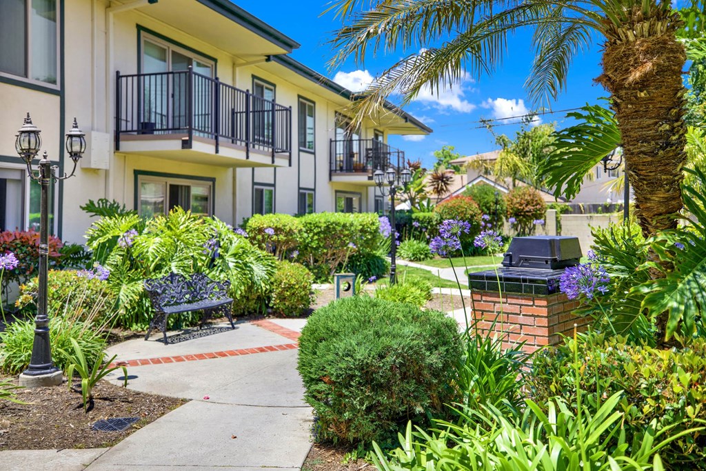 a courtyard with benches and plants in front of an apartment building at Camino de Oro Apartments, Torrance, CA, 90505