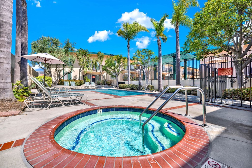 a jacuzzi pool with palm trees and a building in the background at Camino de Oro Apartments, Torrance, California