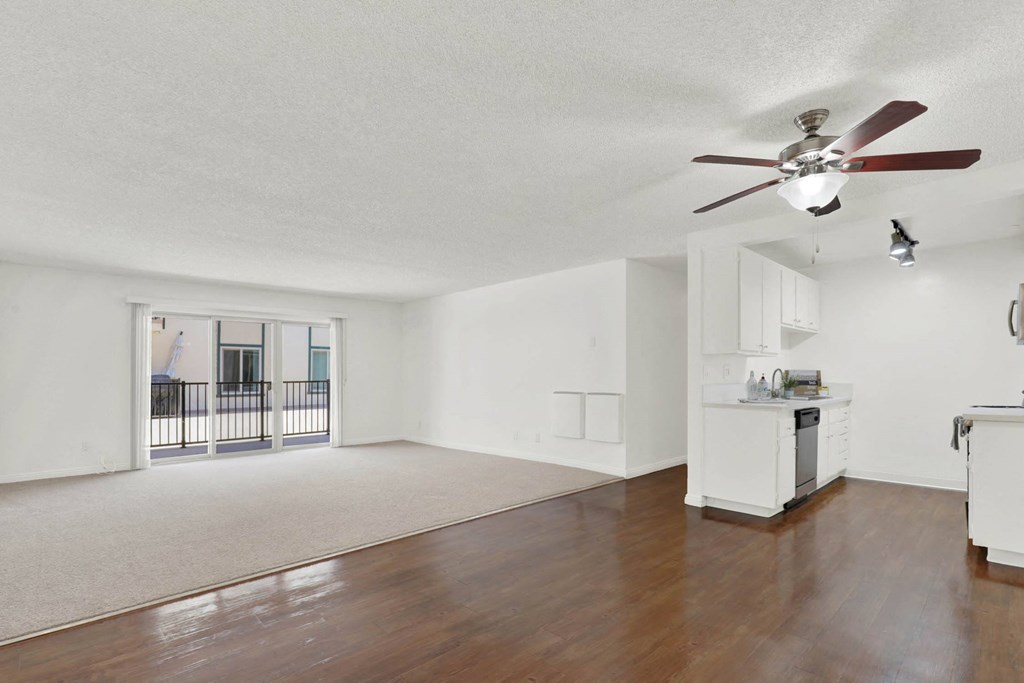 an empty living room with a ceiling fan and a kitchen at Camino de Oro Apartments, Torrance, California