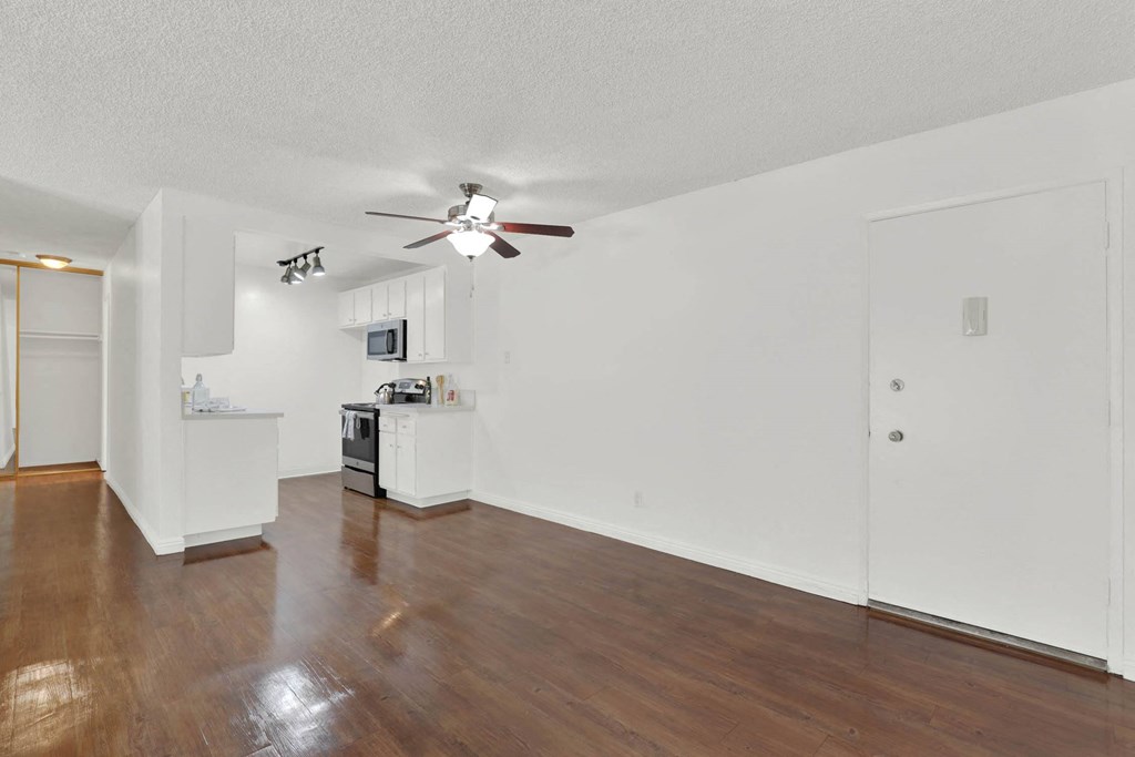 an empty living room with a ceiling fan and a kitchen at Camino de Oro Apartments, Torrance, CA, 90505