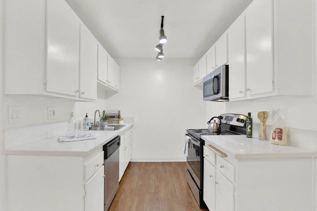 a kitchen with white cabinets and a stove and a microwave at Camino de Oro Apartments, Torrance, CA, 90505