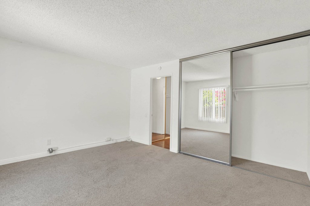 an empty living room with a sliding glass door to a closet at Camino de Oro Apartments, Torrance, CA, 90505