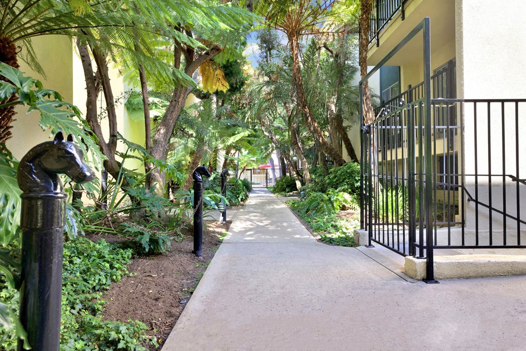 a sidewalk in front of a building with trees and plants at Casa De Oro Apartments, Torrance California