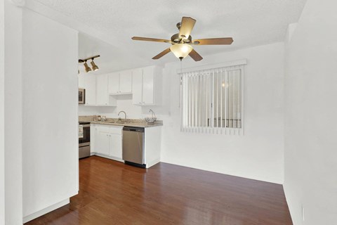 an empty living room and kitchen with a ceiling fan