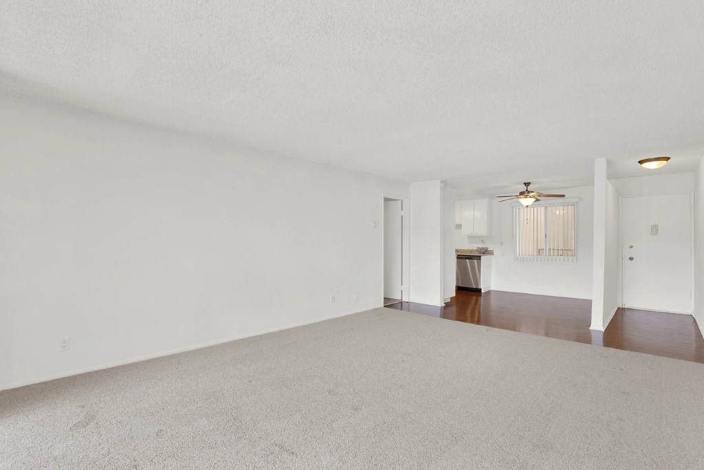 an empty living room with white walls and a ceiling fanat Casa De Oro Apartments, Torrance California