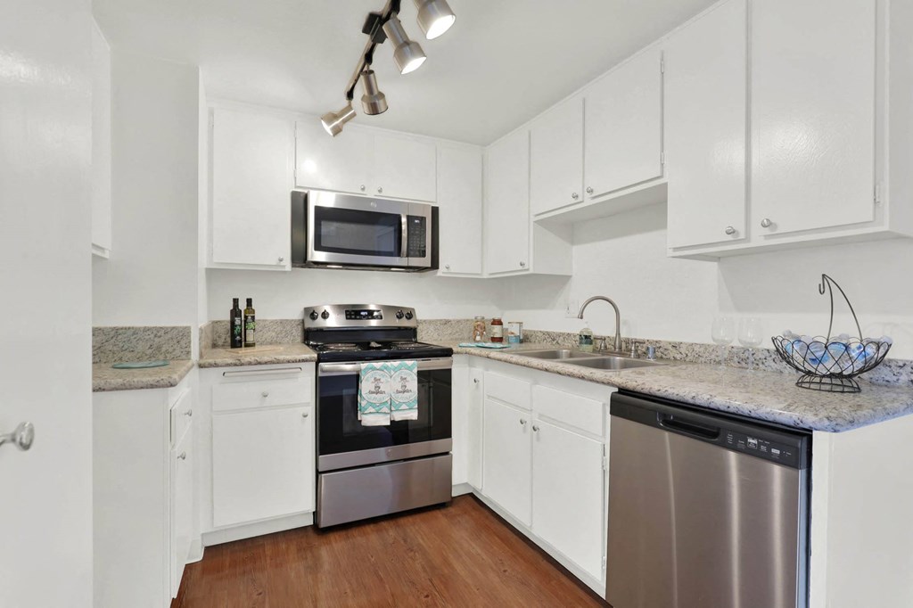 a kitchen with white cabinets and stainless steel appliances at Casa De Oro Apartments, California