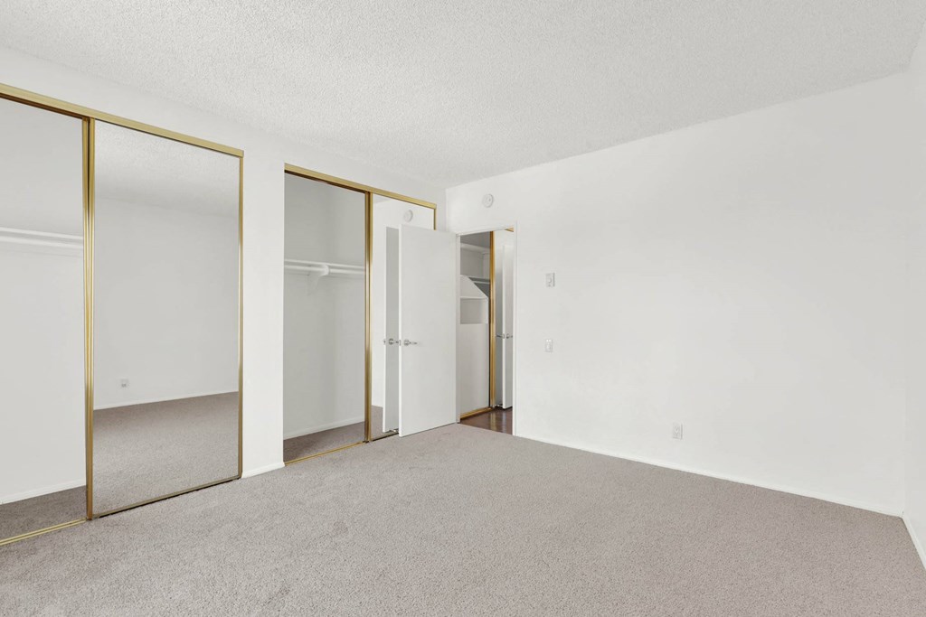 an empty living room with white walls and mirrored closet doors at Casa De Oro Apartments, Torrance, 90505
