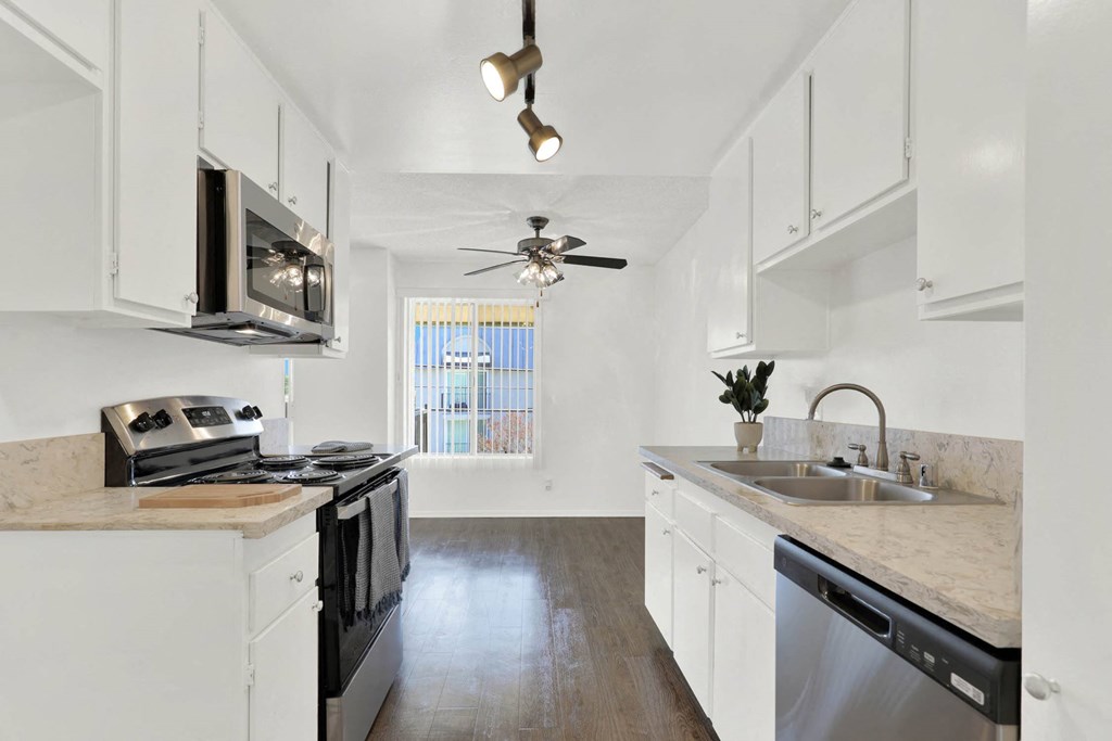 a kitchen with white cabinets and stainless steel appliances at Casa De Oro Apartments, Torrance, CA