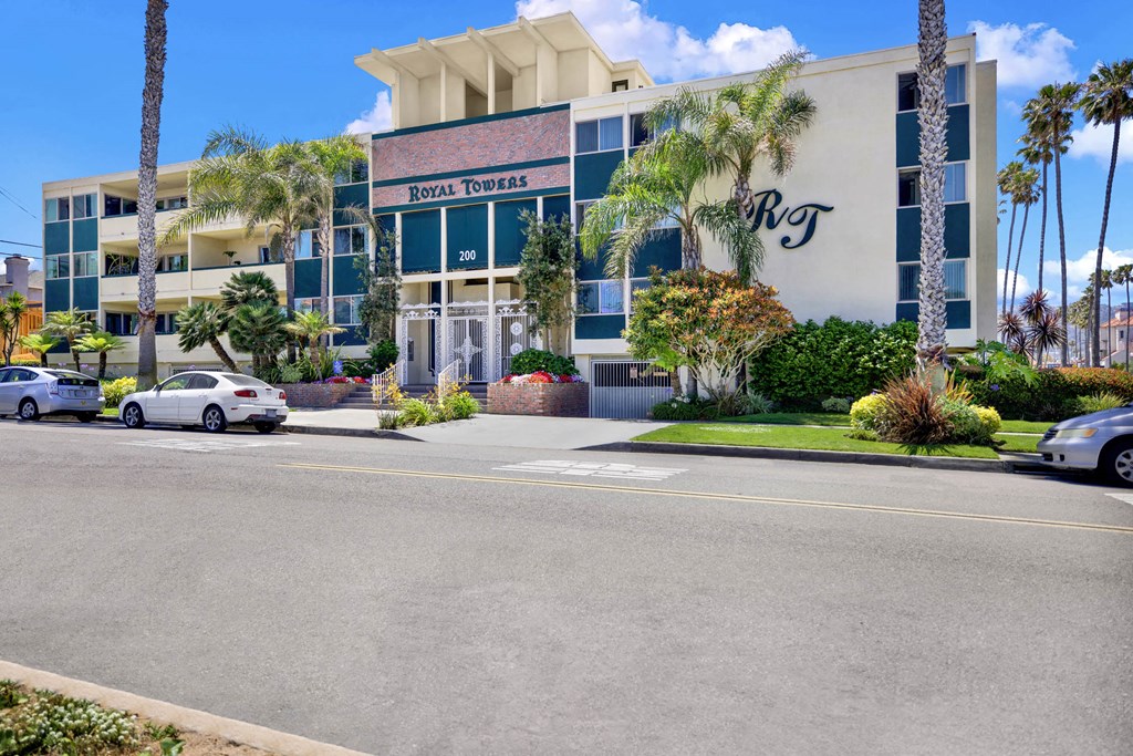 the front of a building with palm trees and cars parked outside  at Royal Towers Apartments, Redondo Beach, CA