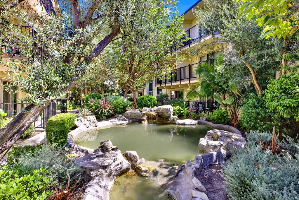 a pond in a garden with trees and rocks at Willow Tree Apartments, Torrance