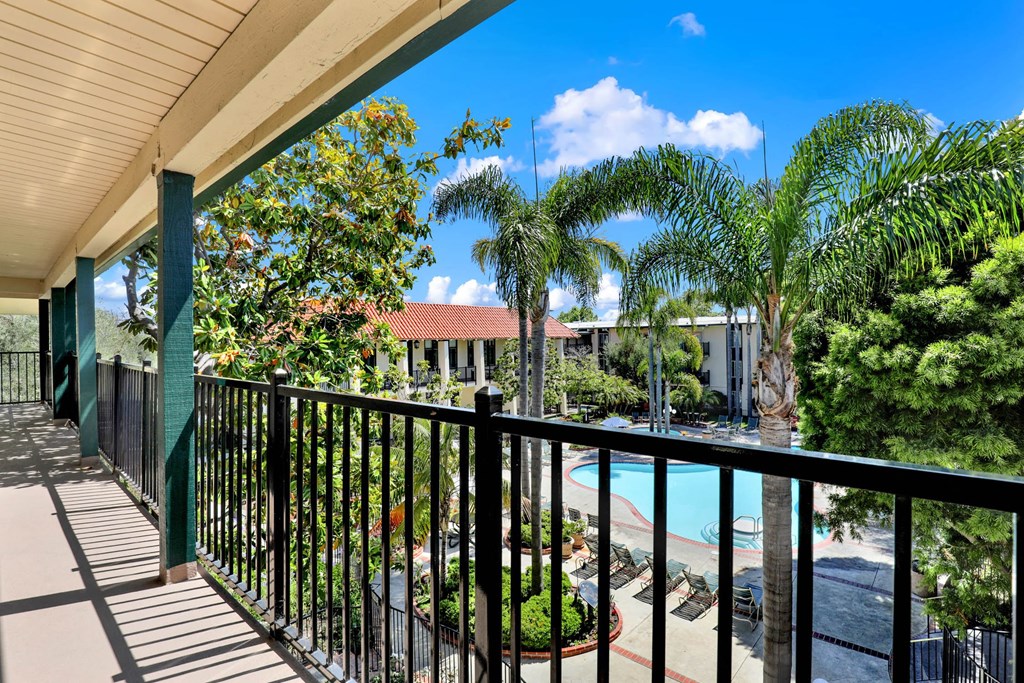 a balcony with a view of a pool and palm trees at Willow Tree Apartments, Torrance, CA, 90505