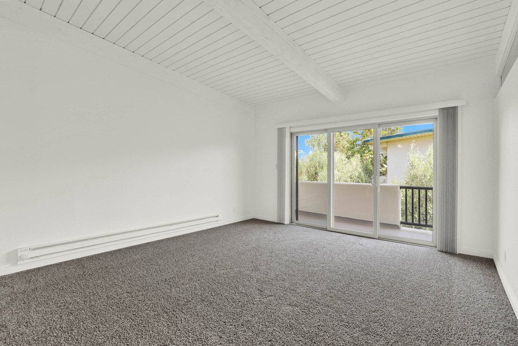an empty living room with carpet and a sliding glass door at Willow Tree Apartments, Torrance
