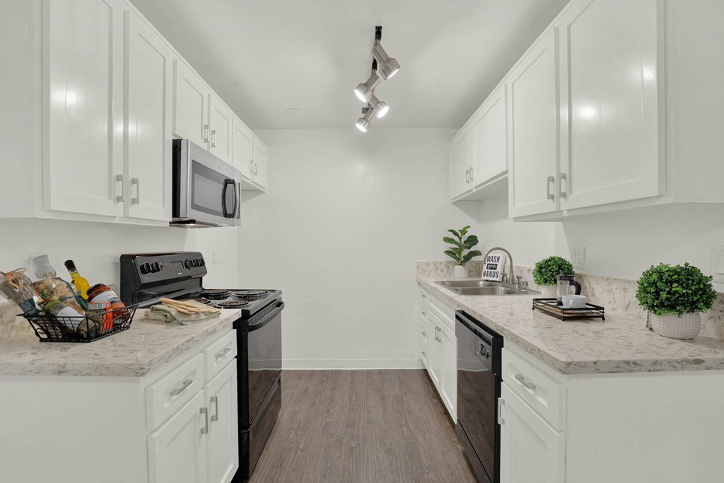 a white kitchen with white cabinets and black appliances  at Willow Tree Apartments, Torrance, CA, 90505