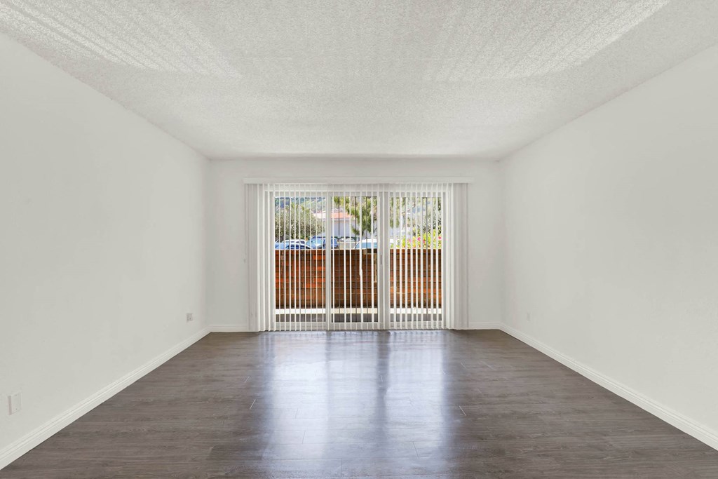 an empty living room with a sliding glass door to a balcony at Willow Tree Apartments, Torrance, CA