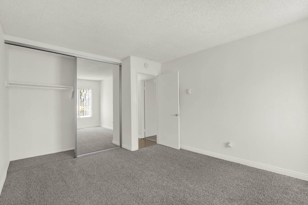 the living room of an apartment with white walls and carpet  at Willow Tree Apartments, California, 90505