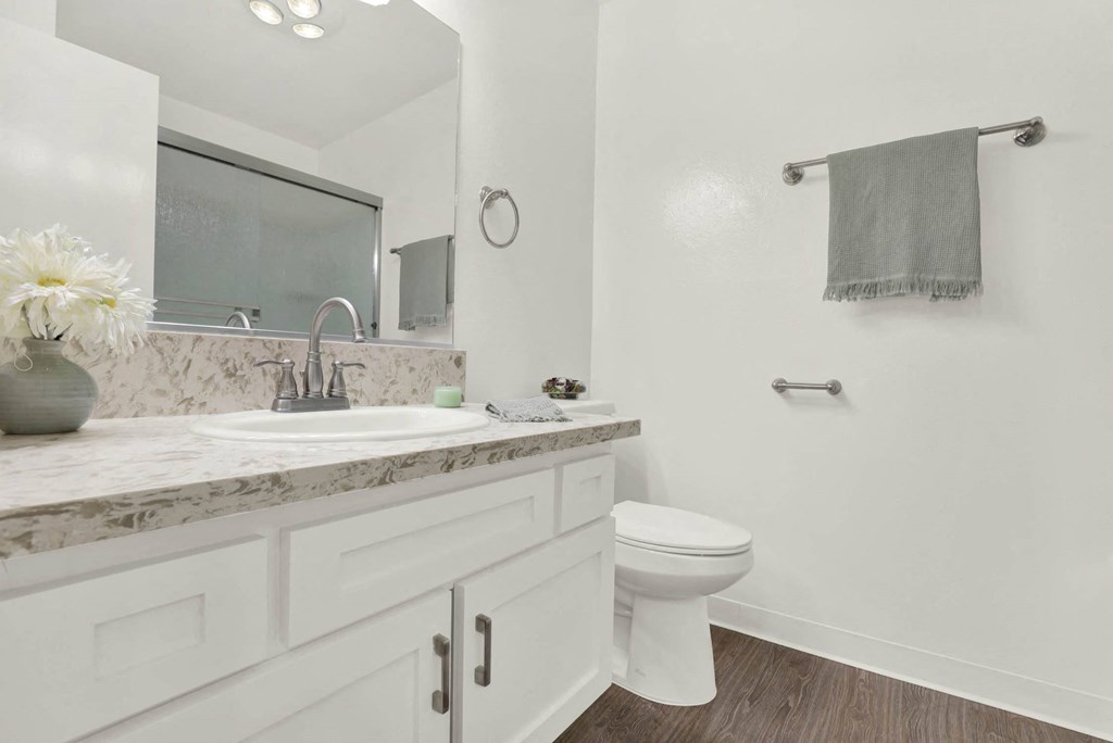 a white bathroom with a sink and a toilet  at Willow Tree Apartments, Torrance, CA