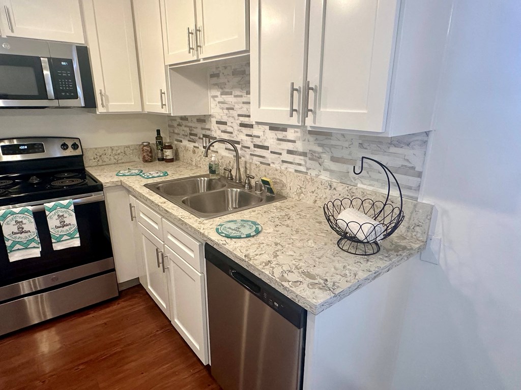 A kitchen with a stove, sink, and cabinets.
