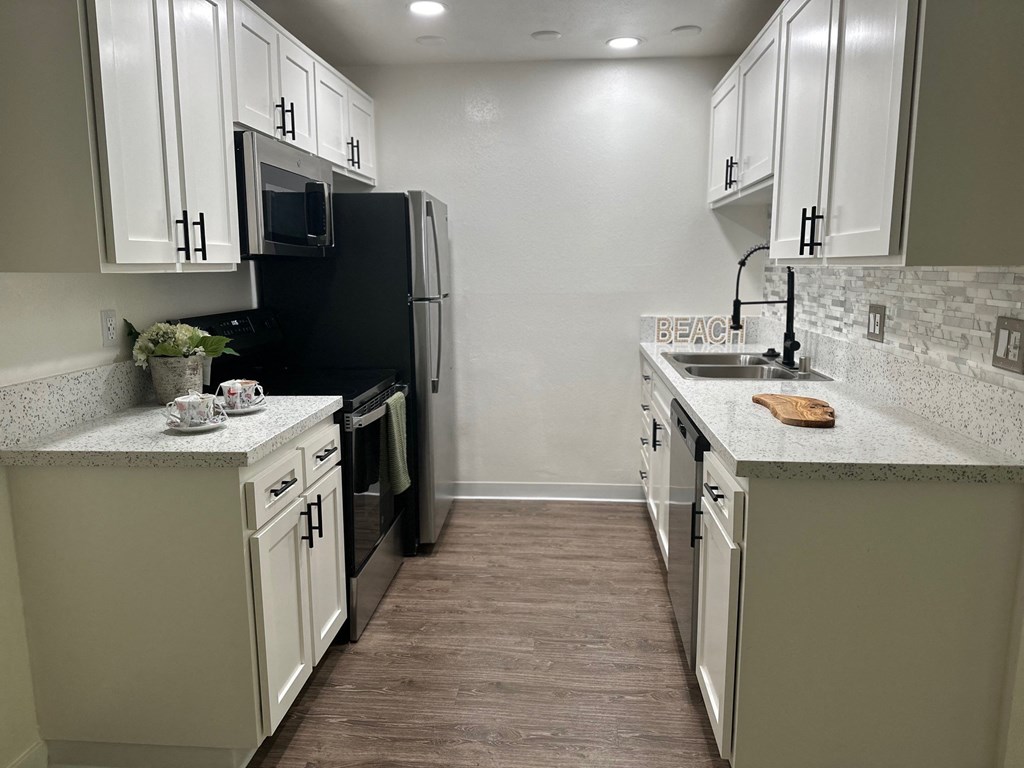 a kitchen with white cabinets and a black stove and refrigerator at Willow Tree Apartments, California, 90505