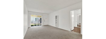 an empty living room with a door to a balcony at Olive Tree Apartments, California