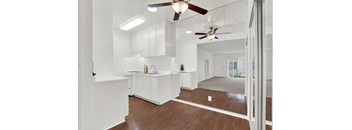 A white kitchen with a wooden floor and a ceiling fan. at Olive Tree Apartments, Torrance, CA