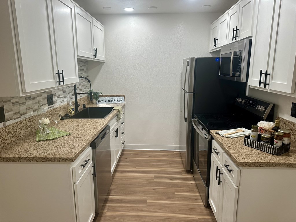 A kitchen with white cabinets and a black fridge at Willow Tree Apartments, California, 90505