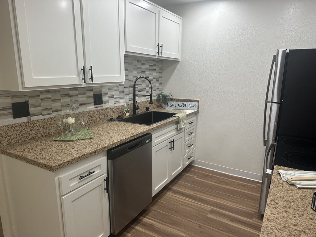 A kitchen with white cabinets and a granite countertop at Willow Tree Apartments, California, 90505