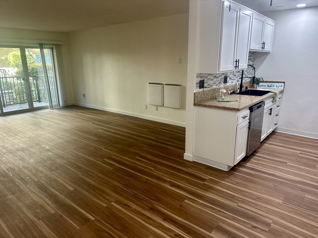 A kitchen with white cabinets and a wooden floor. at Willow Tree Apartments, California, 90505