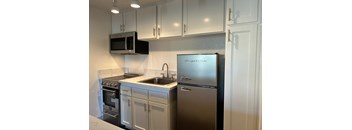 A kitchen with a stainless steel refrigerator and white cabinets.