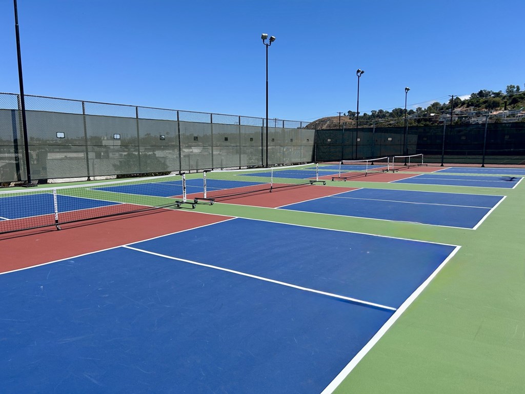 A tennis court with blue and green playing surface and white lines.